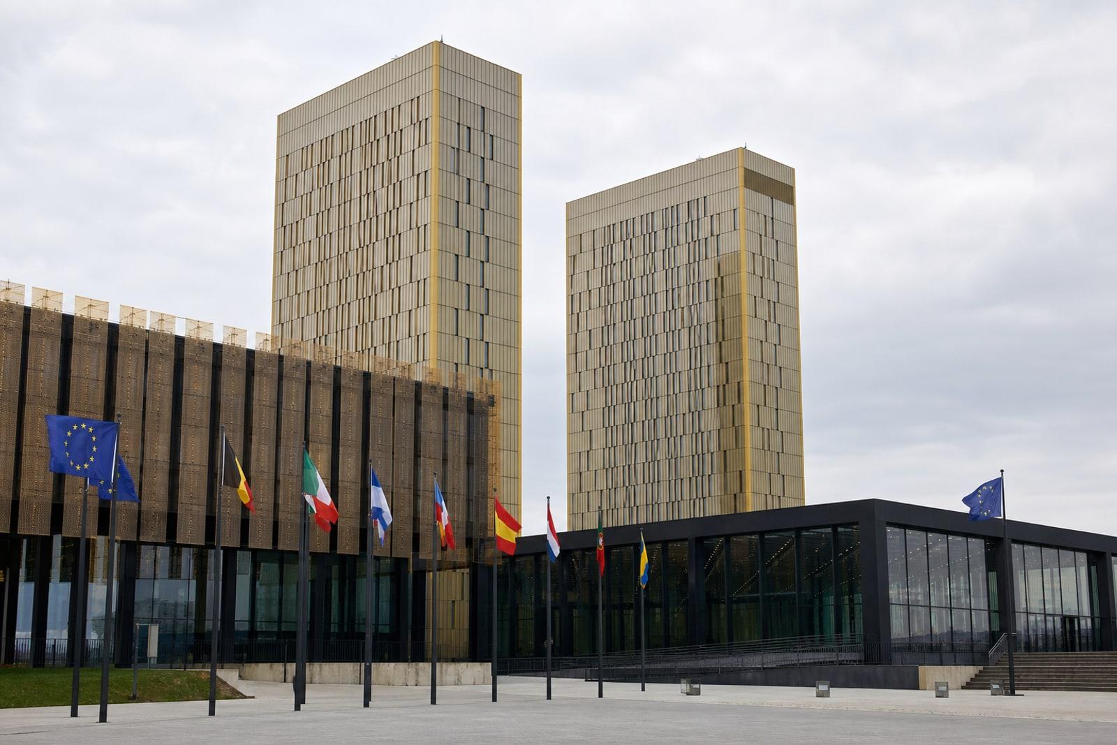 Gebäude des Gerichtshofs der Europäischen Union mit den vergoldeten Türmen auf dem Kirchberg-Plateau in Luxemburg-Stadt, davor EU-Flaggen