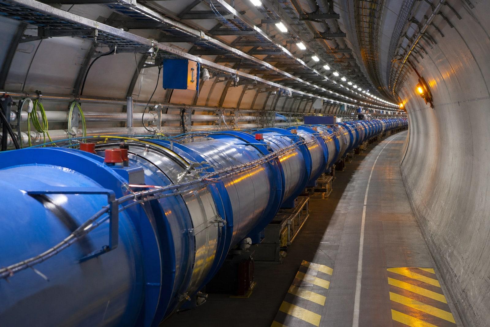 The Large Hadron Collider tunnel at CERN, lined with blue cylindrical superconducting magnets curving along the underground ring.