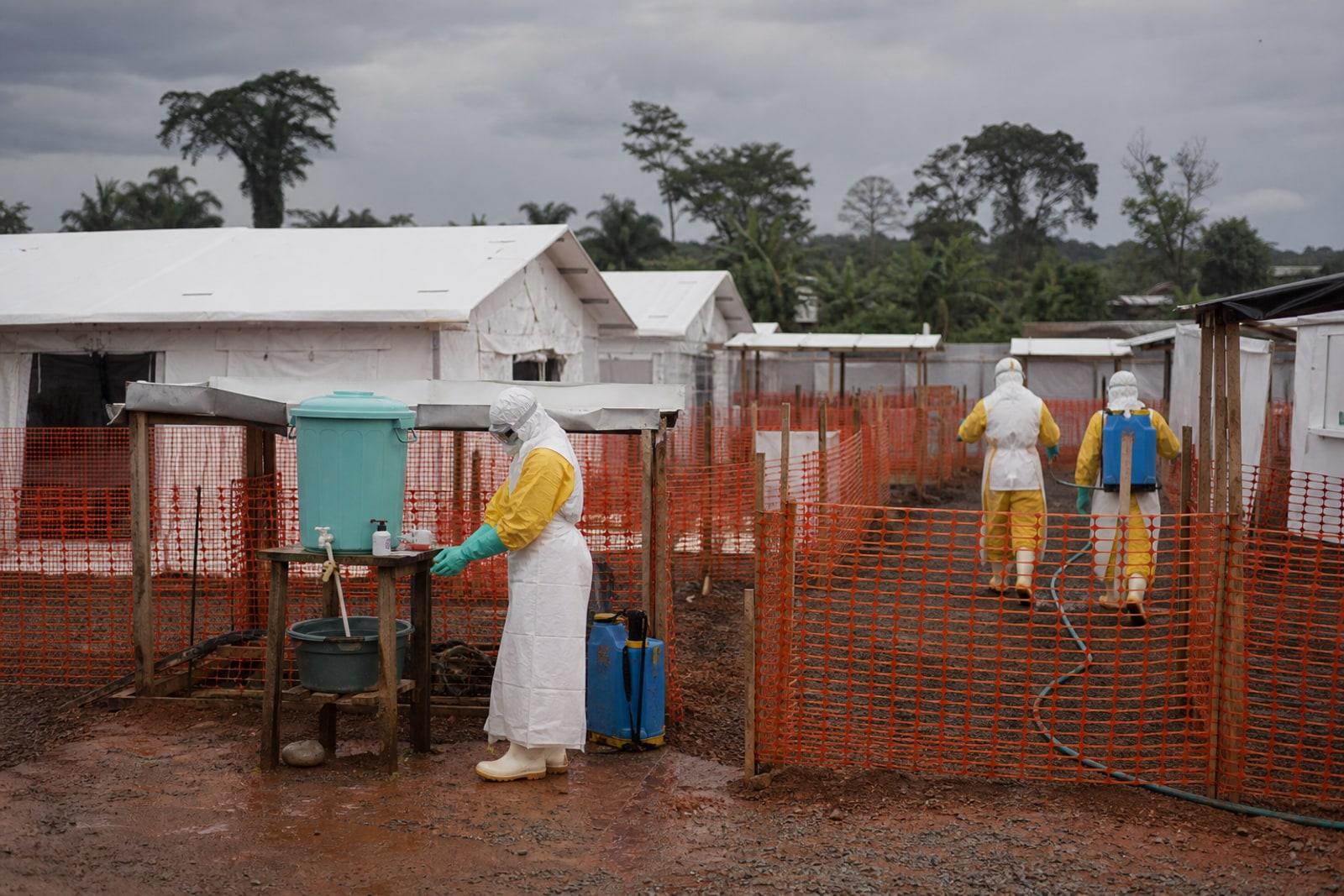 White tented Ebola isolation wards behind orange plastic fencing with health workers in full protective suits near Bunia, eastern DRC.