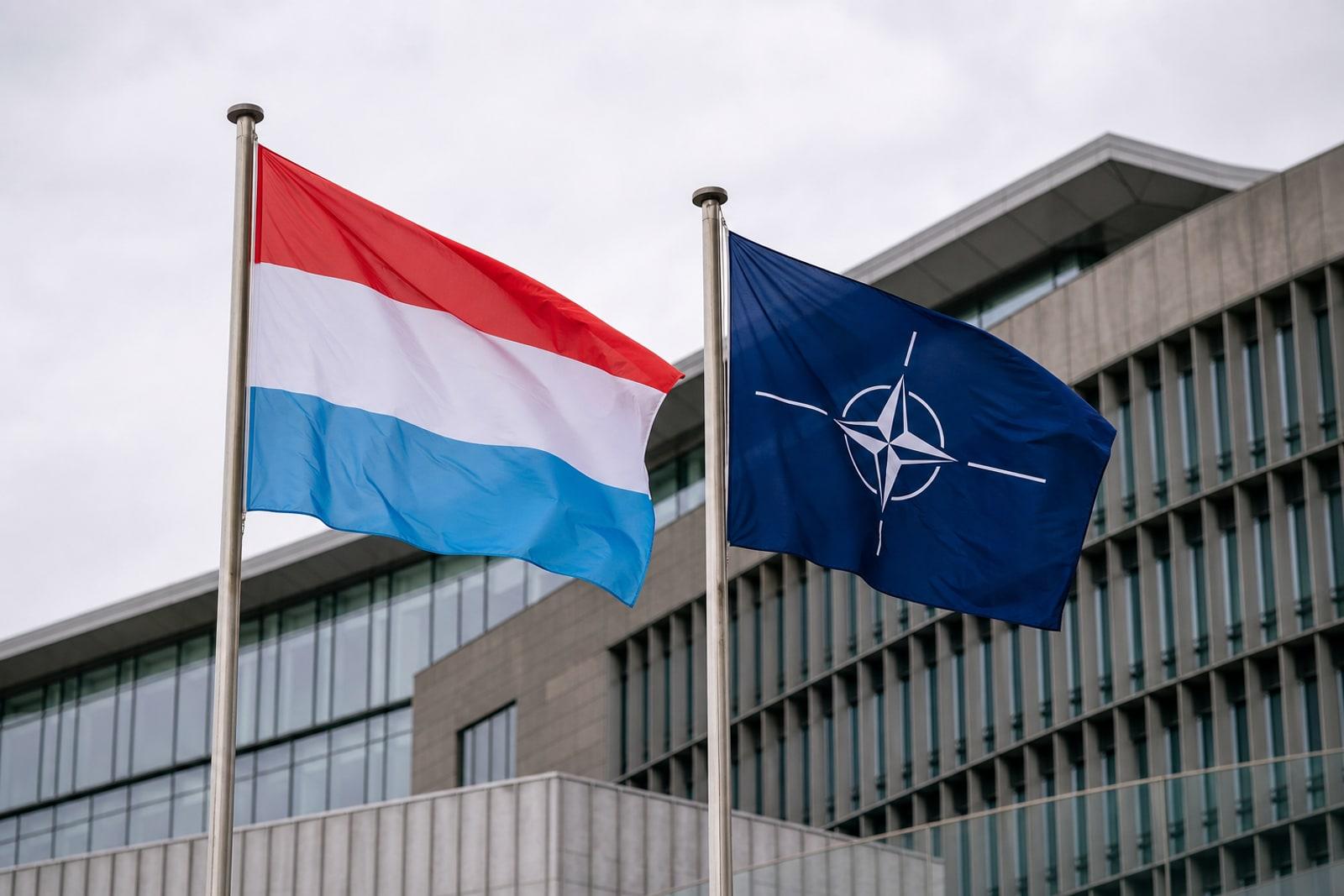 D'Lëtzebuerger Fändel an den NATO-Fändel niewenteneen op Fändelpäl virun engem Regierungsgebai um Kirchberg zu Lëtzebuerg-Stad.
