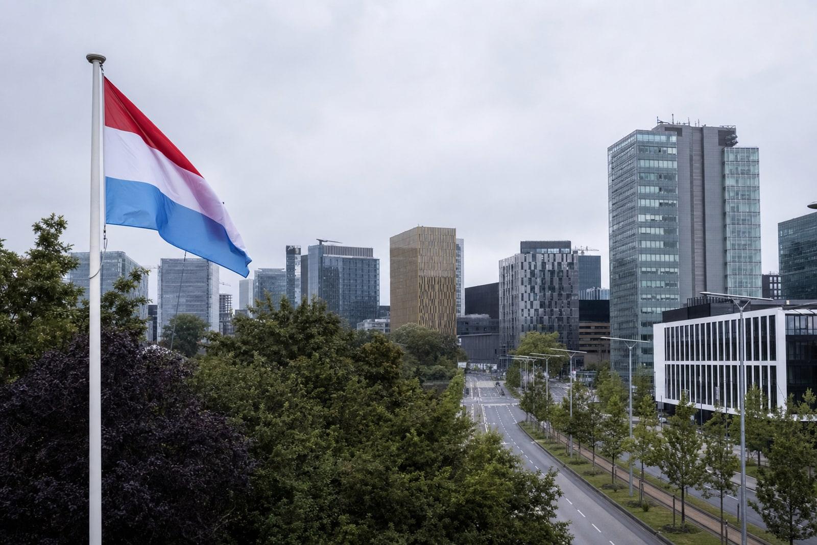 Modern glass office towers of Luxembourg City's Kirchberg financial district under an overcast sky.
