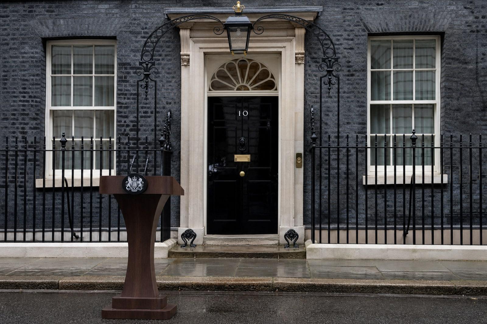 The glossy black front door of 10 Downing Street with its white number 10, brass letterbox and lion's-head knocker.
