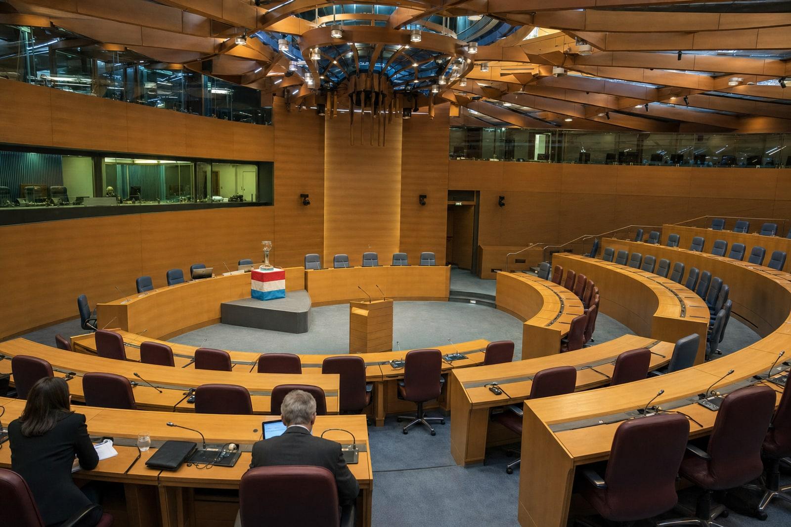 The tiered Hémicycle auditorium of the European Convention Centre in Luxembourg-Kirchberg, with a speaker's rostrum and a glass award trophy on stage.