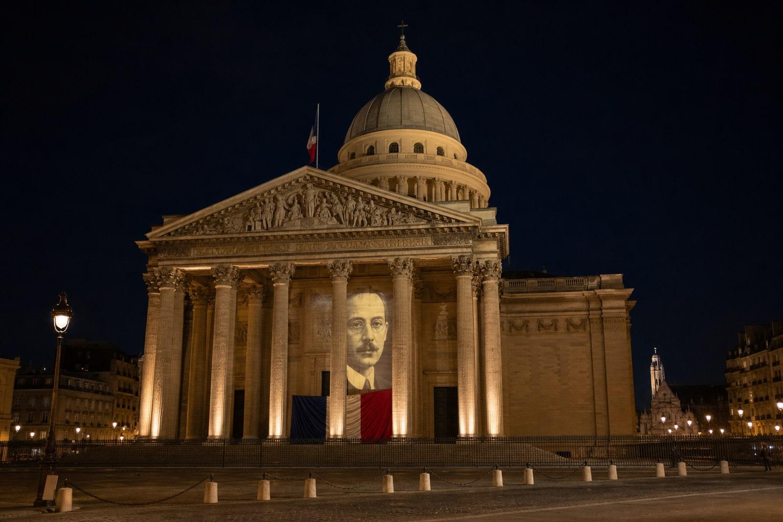 The floodlit neoclassical Panthéon in Paris at night with a projected portrait of Marc Bloch between its columns