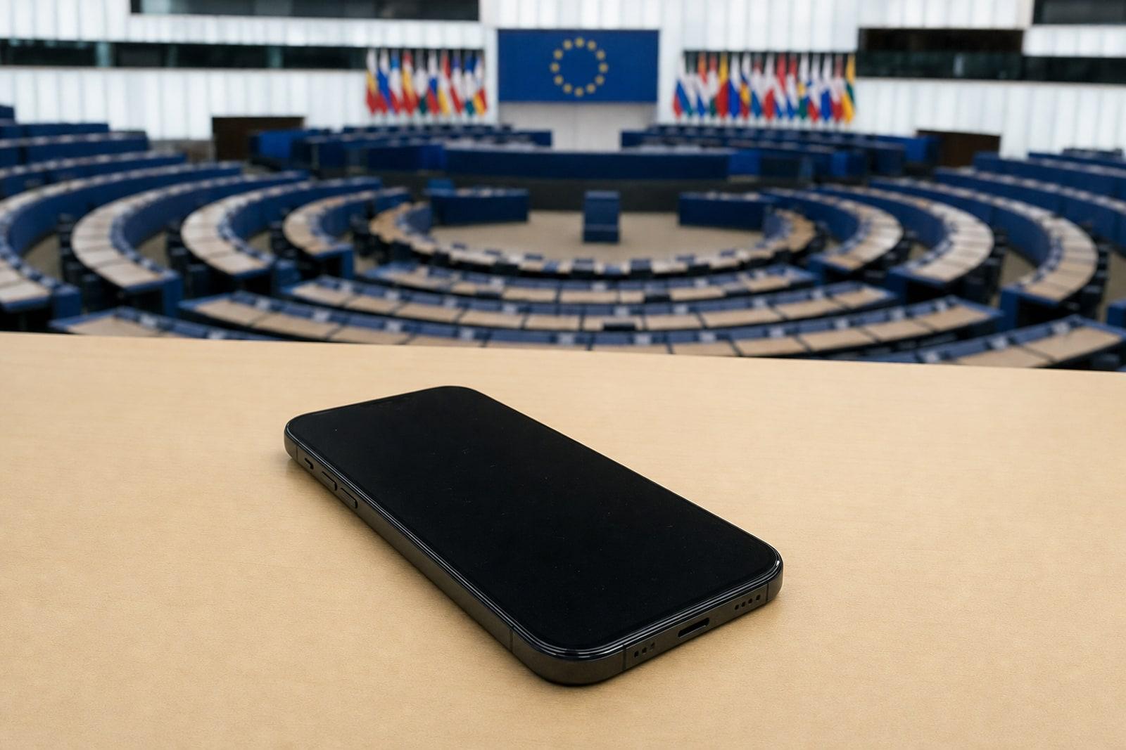 Un smartphone posé sur un pupitre dans l'hémicycle aux sièges bleus du Parlement européen
