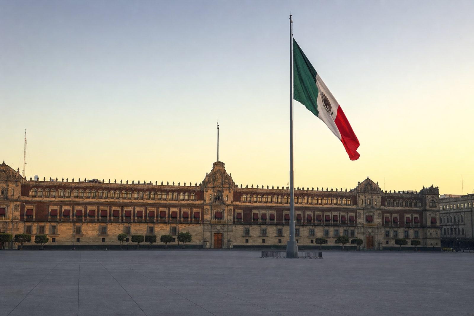 The red stone facade of Mexico's National Palace on the Zócalo square in Mexico City, with the giant Mexican flag flying