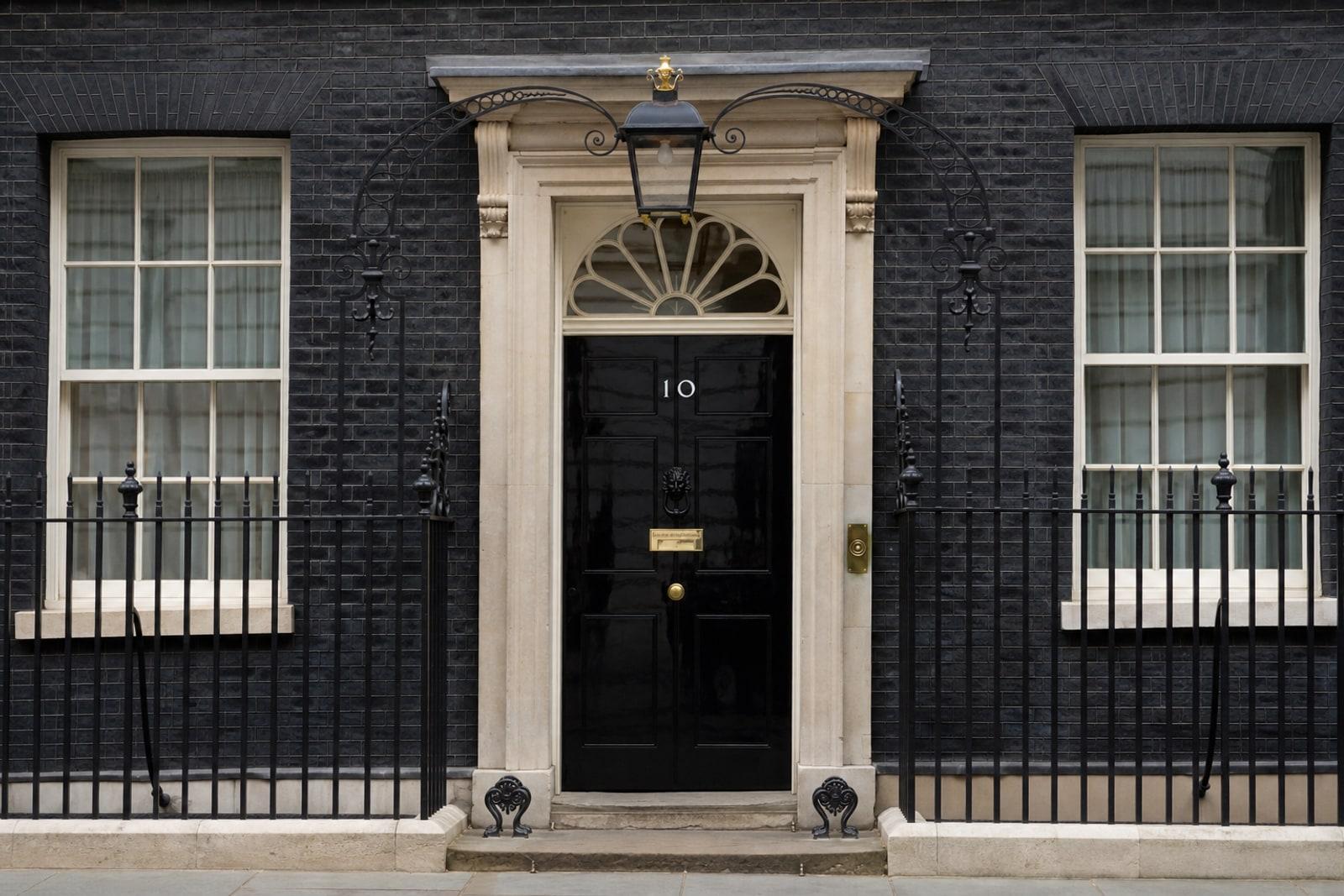The glossy black front door of 10 Downing Street with its white '10' numeral and brass letterbox.