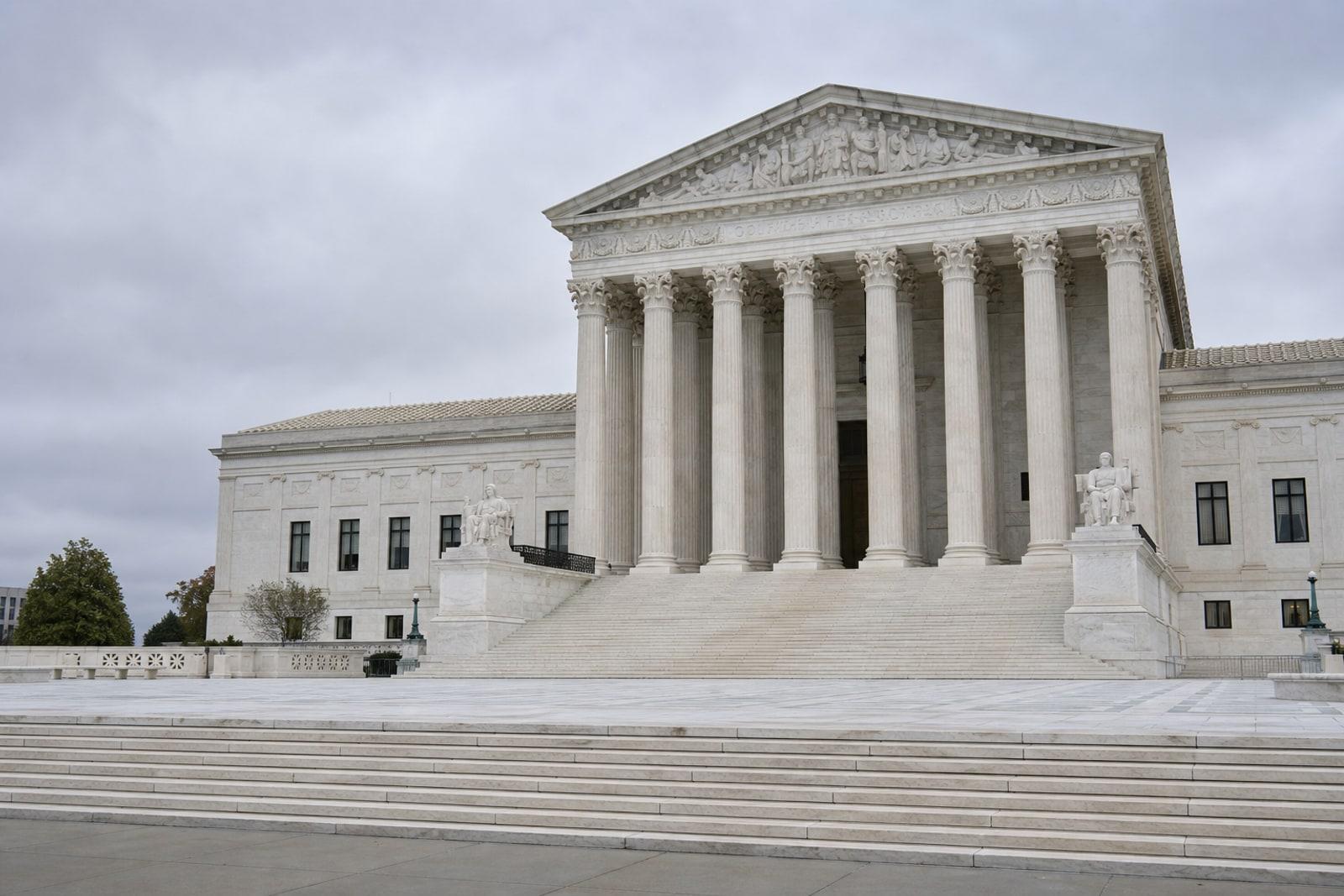 The white marble west facade and columned steps of the United States Supreme Court Building in Washington under overcast light.
