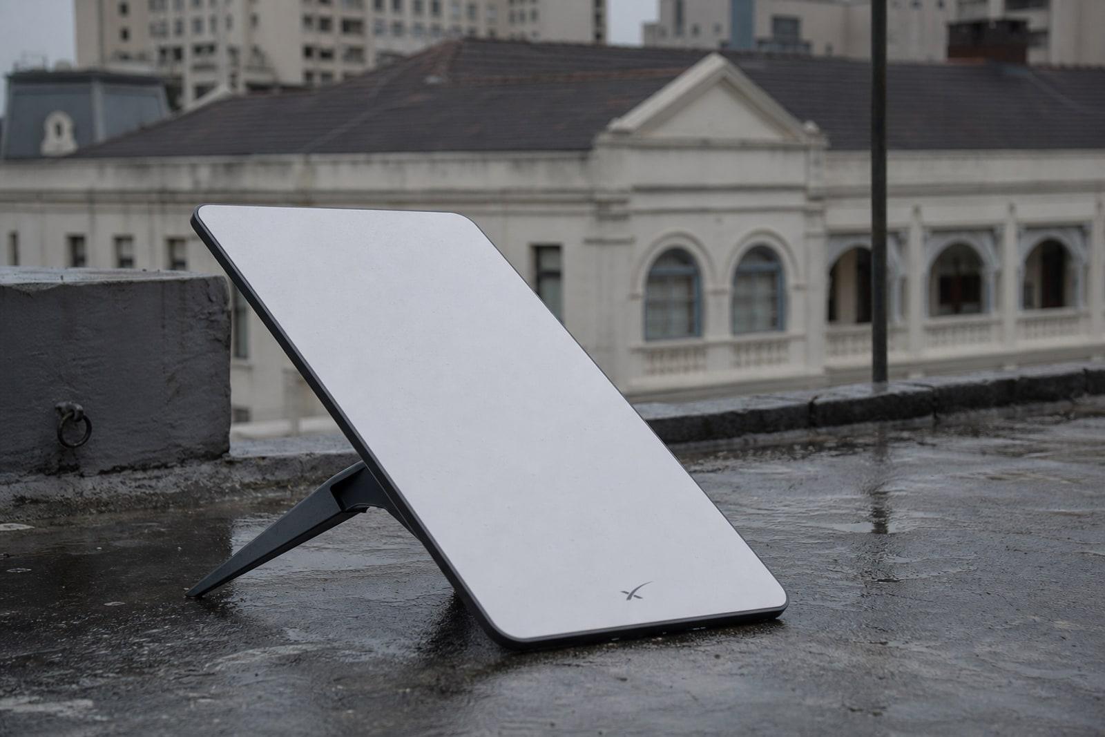 White rectangular Starlink terminal on a wet Taipei rooftop with the Legislative Yuan in the background