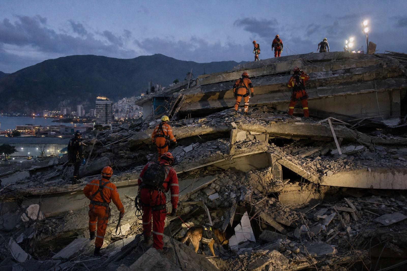 Internationale Rettungskräfte und ein Suchhund durchsuchen die Trümmer eines eingestürzten Wohnhauses in La Guaira, Venezuela.
